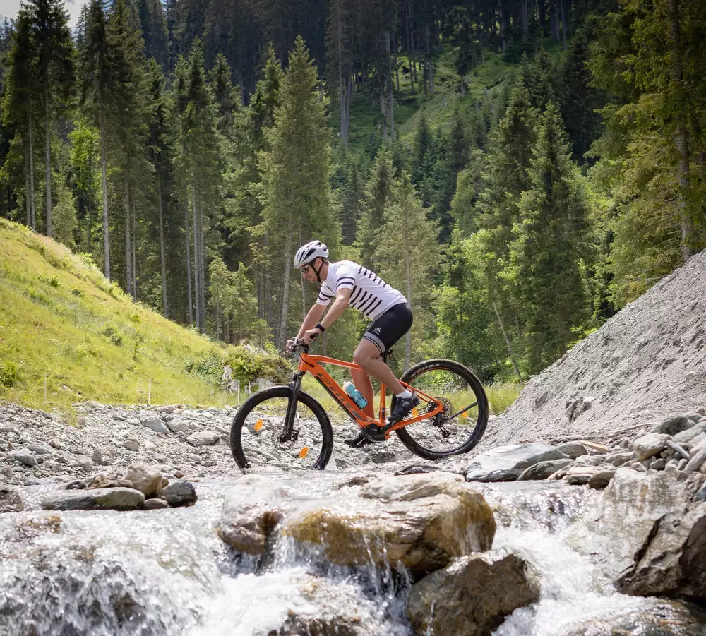 Radfahrer überquert Gebirgsfluss