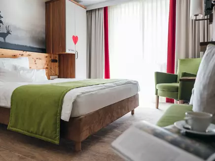 Helles Zimmer mit großen Fenstern und grünen Akzenten