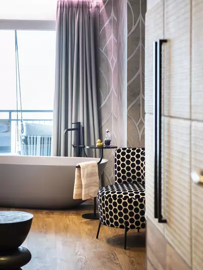 Modernes Zimmerdetail mit freistehender Badewanne, Sessel und Balkonblick