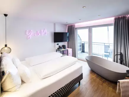 Hotelzimmer mit Badewanne am Fenster und moderner Einrichtung