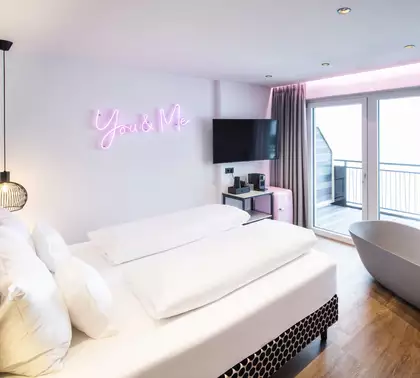 Hotelzimmer mit Badewanne am Fenster und moderner Einrichtung